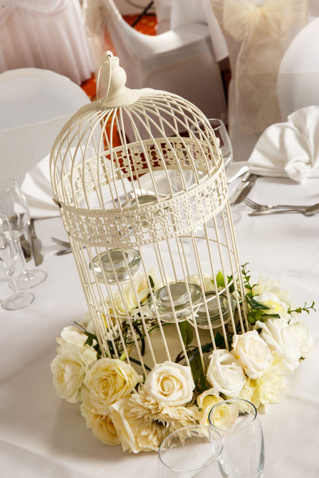 Close up of white bird cage with white flowers as table decoration