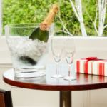 Mercier champagne in ice bucket with two glasses and a box of chocolates on a table by the window