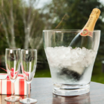 Mercier champagne in ice bucket in garden with two glasses and a box of chocolates
